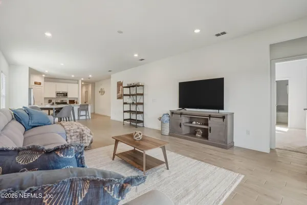 a living room with furniture and a dining table with kitchen view