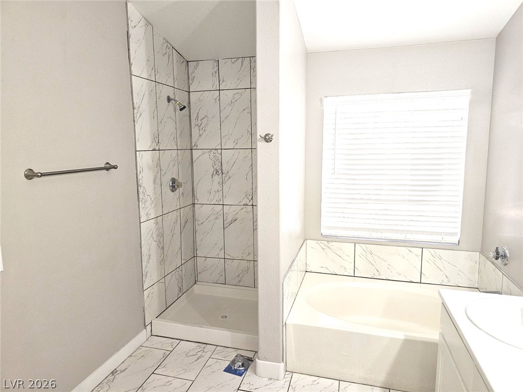 1418 Reebok Terrace Henderson, NV 89014 - Photo 25 of 38 Marble-look tile and a spacious soaking tub elevate this pristine bathroom.