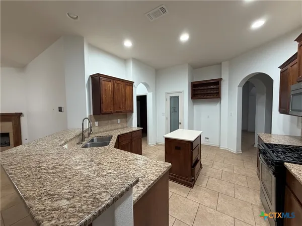a kitchen with granite countertop a sink and a refrigerator