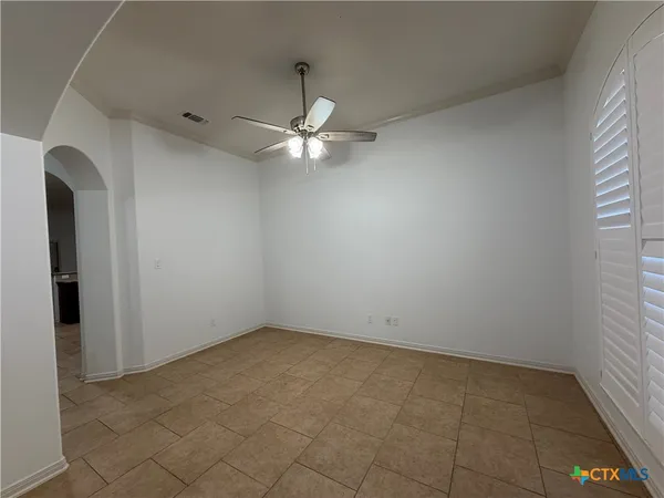 an empty room with a chandelier fan and windows