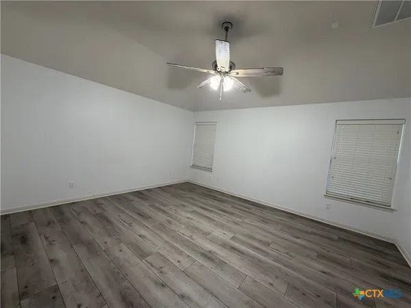 an empty room with wooden floor and ceiling fan