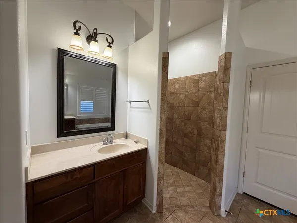 a bathroom with a sink vanity granite shower and a mirror