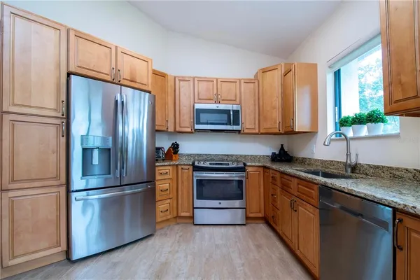 a kitchen with granite countertop stainless steel appliances a sink and a window