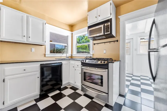 a kitchen with granite countertop a stove a sink and a refrigerator with wooden floor