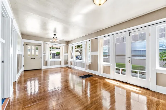 a view of an empty room with wooden floor and a window