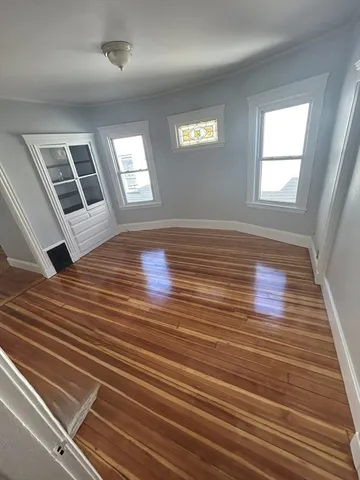 a view of an empty room with wooden floor and window