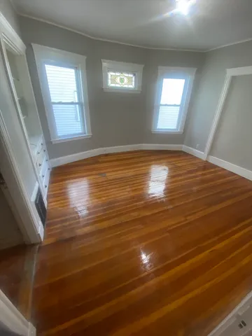 a view of empty room with window and wooden floor