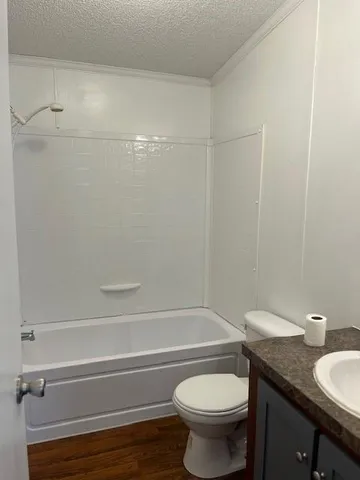 a bathroom with a granite countertop bathtub shower sink vanity and toilet