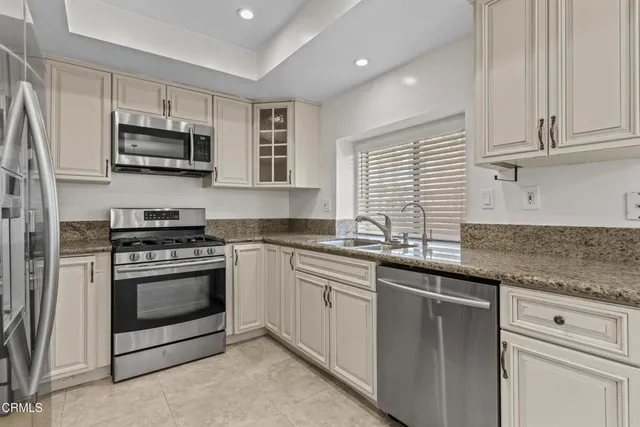 a kitchen with stainless steel appliances granite countertop a sink dishwasher a stove and a microwave oven with cabinets