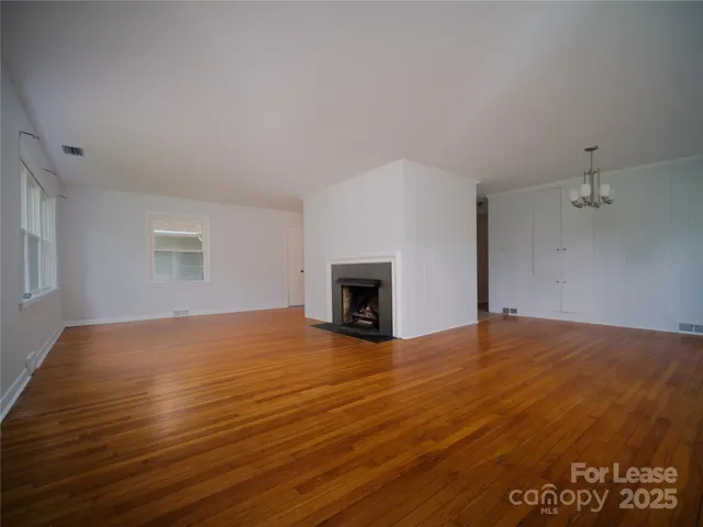 a view of empty room with wooden floor and fireplace