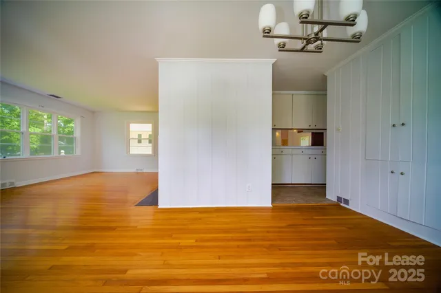 a view of empty room with window and wooden floor