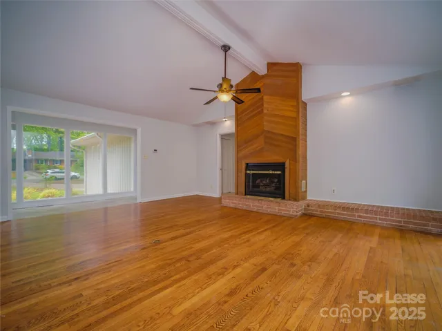 a view of empty room with a fireplace and wooden floor