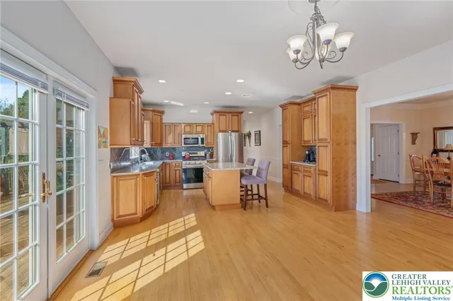 a kitchen with stainless steel appliances granite countertop a refrigerator a sink dishwasher a dining table and chairs with wooden floor