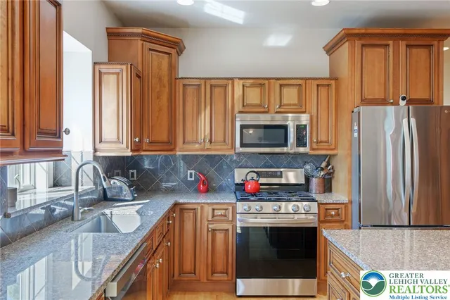 a kitchen with stainless steel appliances granite countertop a refrigerator a stove top oven a sink and dishwasher