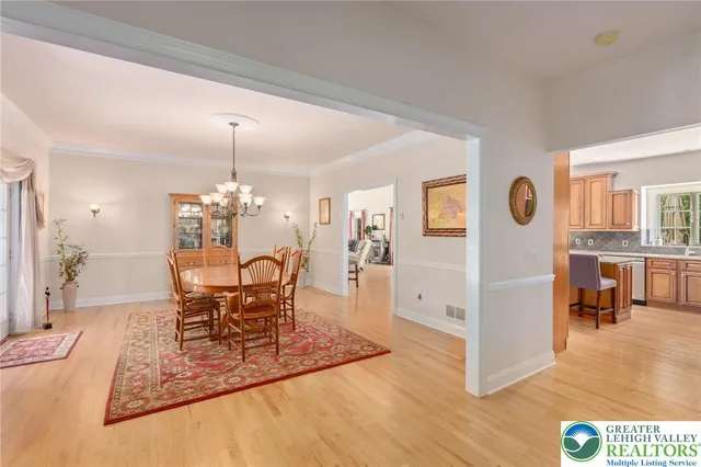 a dining room with wooden floor a chandelier a wooden table and chairs