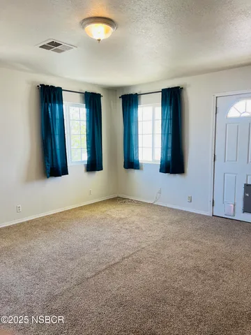 a view of an empty room with window and bathroom