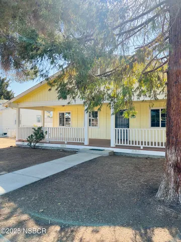 a front view of a house with a garden and trees