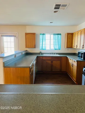 a kitchen with stainless steel appliances granite countertop a sink window and cabinets