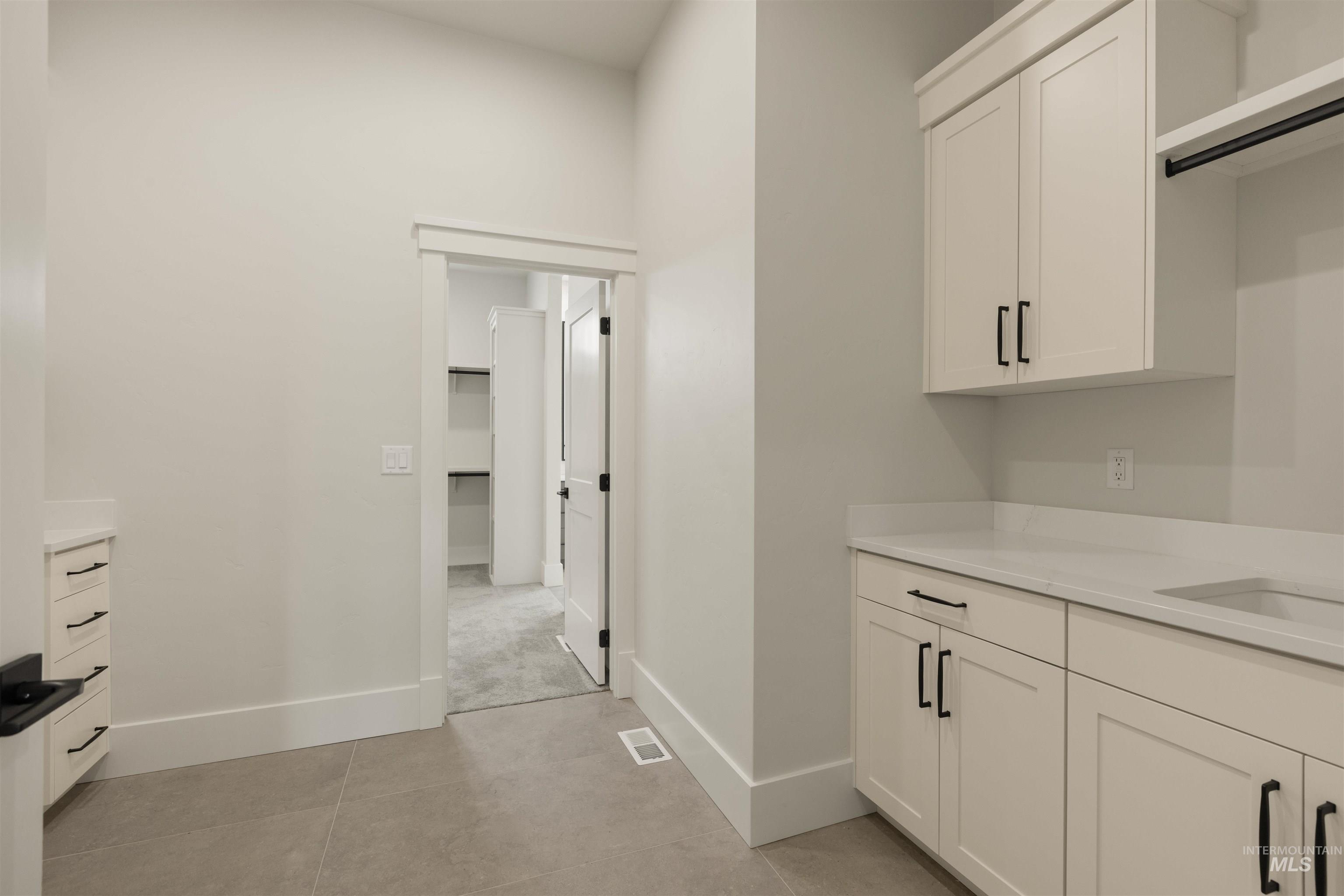 2595 East Tenzing Drive Meridian, ID 83642 - Photo 21 of 32 Bar area featuring white cabinets, light stone countertops, and light tile patterned floors