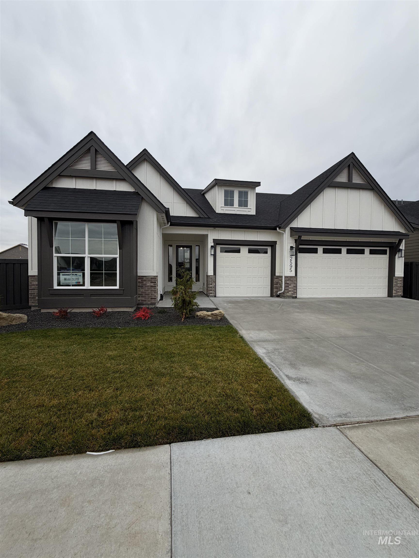 2595 East Tenzing Drive Meridian, ID 83642 - Photo 31 of 32 View of front of house with concrete driveway, a front lawn, stone siding, board and batten siding, and an attached garage