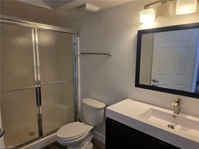 a bathroom with a sink a mirror a toilet and shower