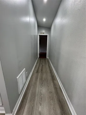 a view of an empty room with wooden floor and stairs