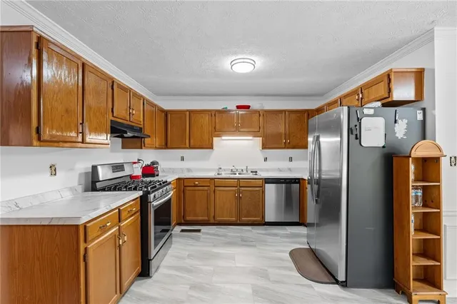a kitchen with granite countertop stainless steel appliances a sink refrigerator and microwave