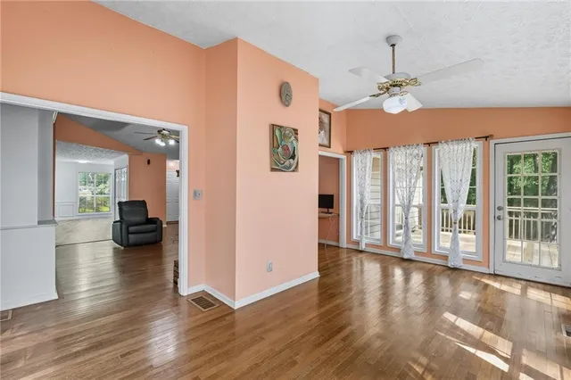 a view of a livingroom with wooden floor a ceiling fan and windows