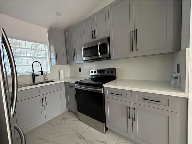 a kitchen with stainless steel appliances granite countertop white cabinets and a stove top oven