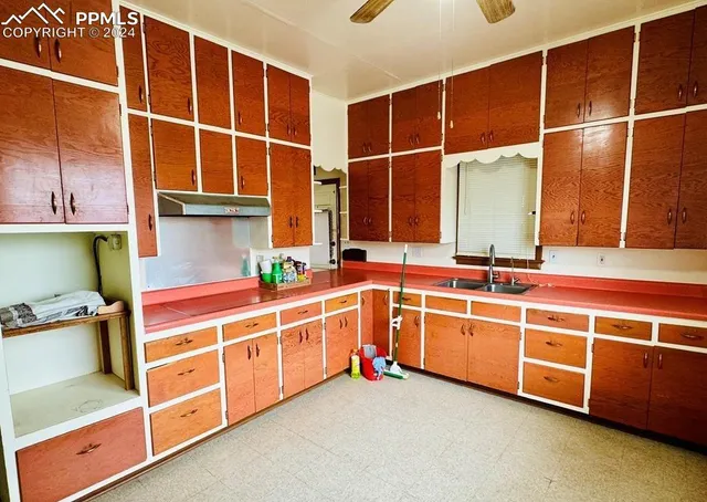 an empty room with wooden floor chandelier fan and windows