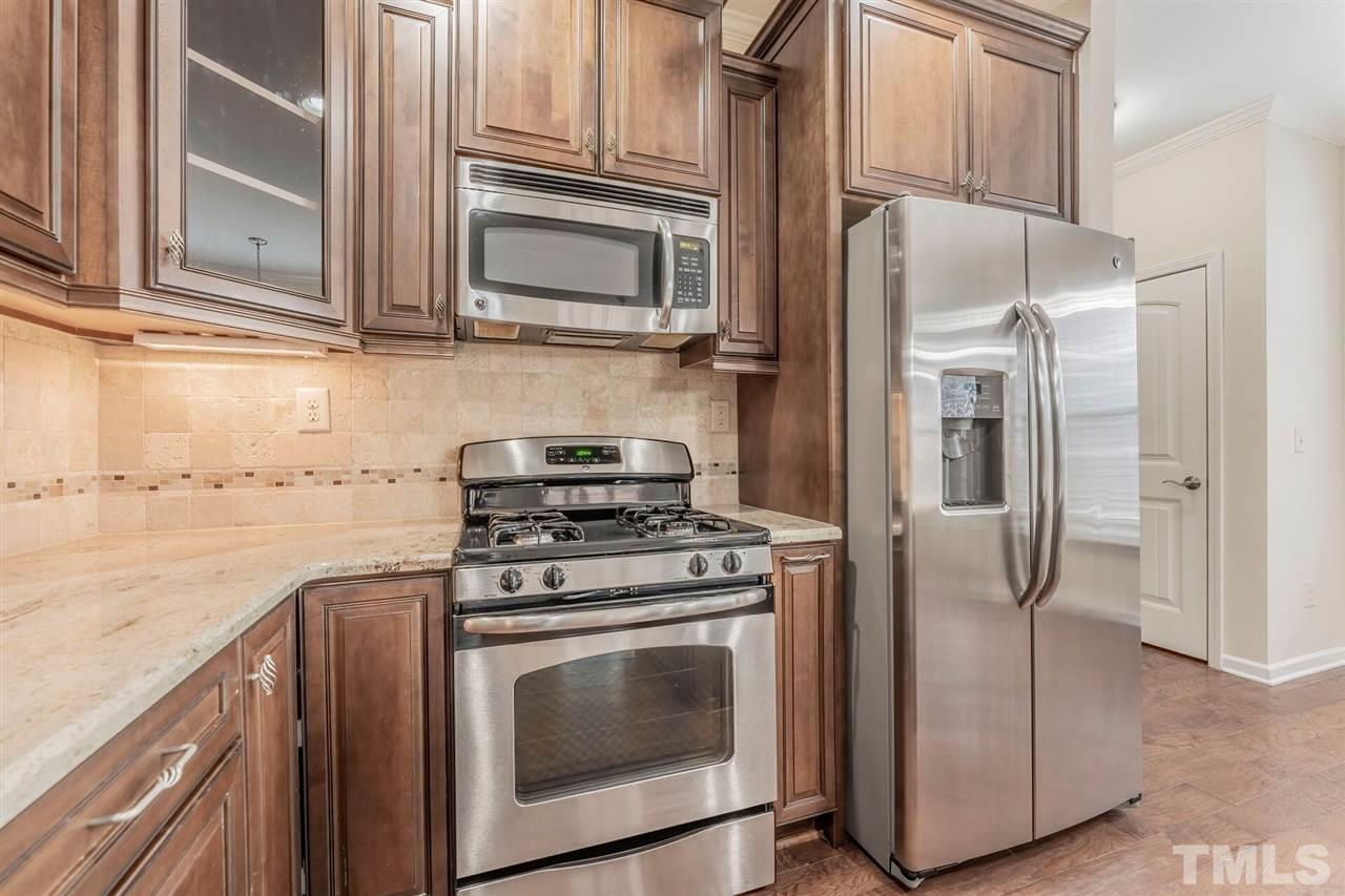 2431 Swans Rest Way Raleigh, NC 27606 - Photo 7 of 25 a kitchen with stainless steel appliances granite countertop a stove a refrigerator and a microwave