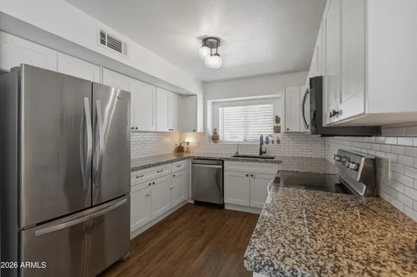 a kitchen with stainless steel appliances granite countertop a refrigerator a stove and a sink