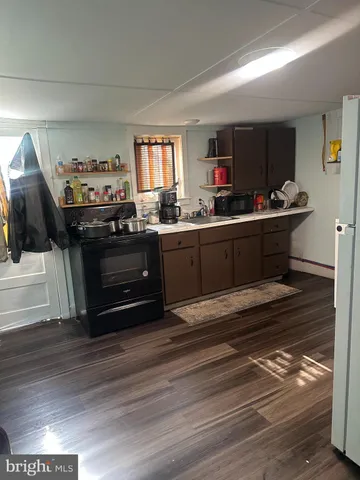 a kitchen view with wooden floor and black appliances