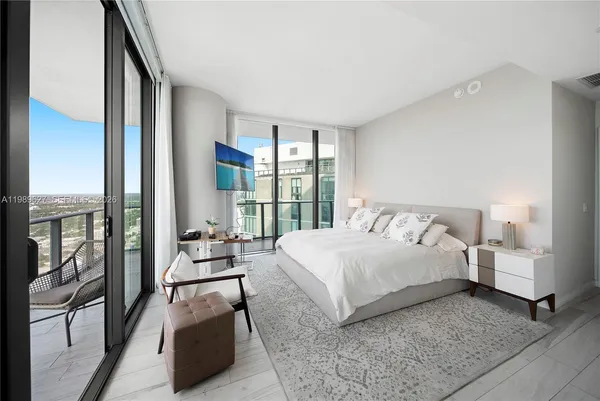 a bedroom with a bed and large window with balcony view