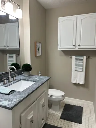 a bathroom with a granite countertop sink a toilet and a mirror