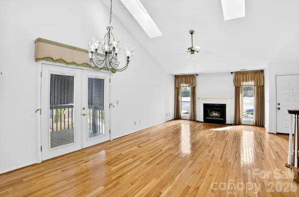 a view of an empty room with wooden floor and a fireplace