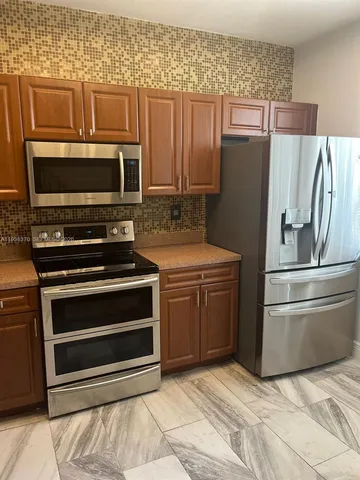 a kitchen with granite countertop a refrigerator and a stove top oven