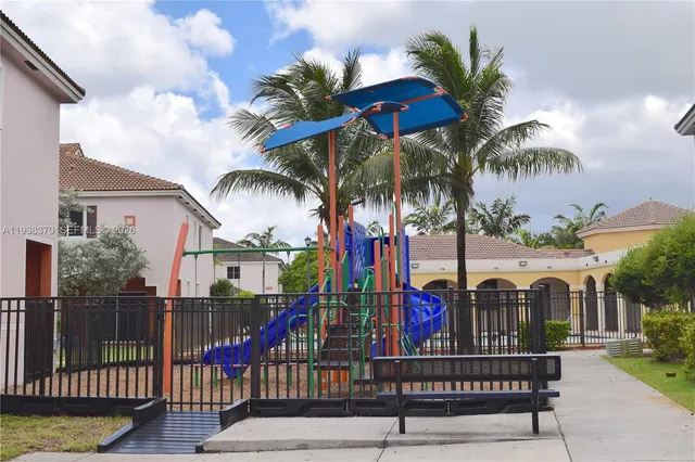 a view of a house with large trees and playing area
