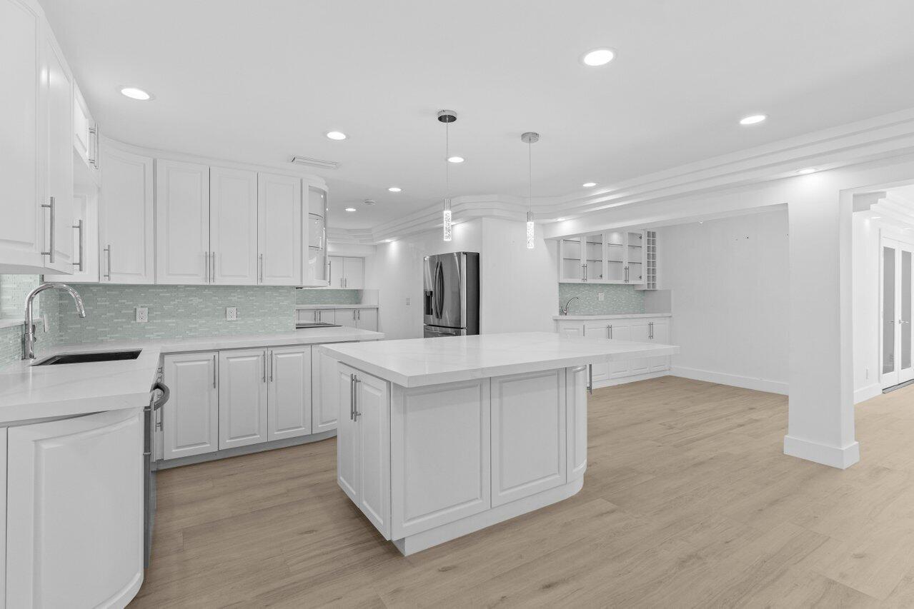 2611 Northeast 49th Street Lighthouse Point, FL 33064 - Photo 13 of 56 a kitchen with kitchen island a sink stainless steel appliances and white cabinets