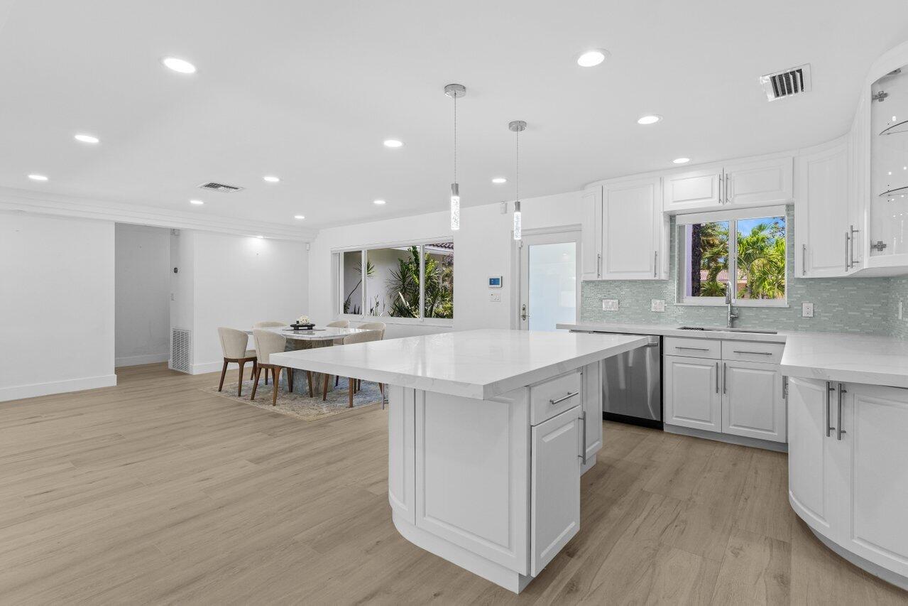 2611 Northeast 49th Street Lighthouse Point, FL 33064 - Photo 15 of 56 a large kitchen with kitchen island a sink a stove a dining table and chairs