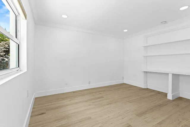 a view of an empty room with wooden floor and a window