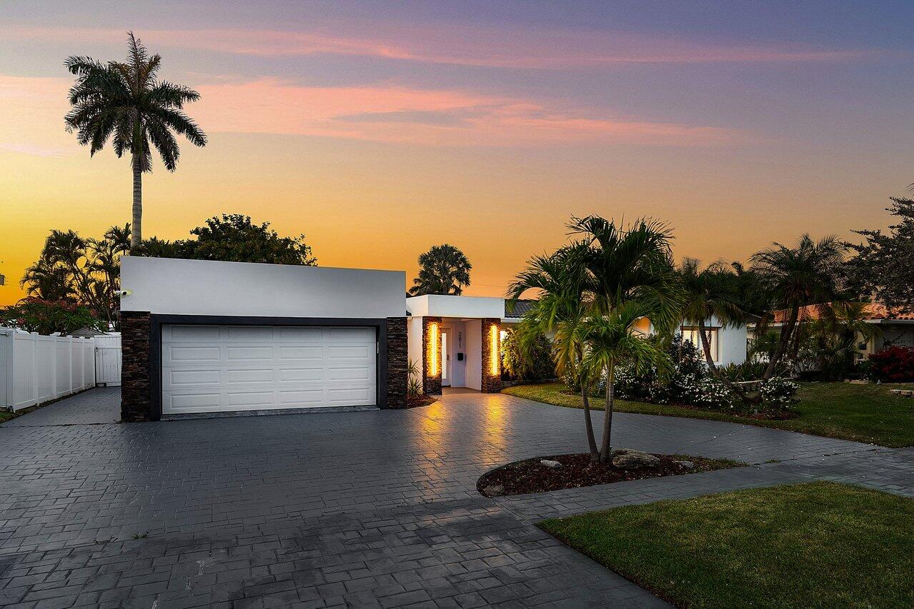 2611 Northeast 49th Street Lighthouse Point, FL 33064 - Photo 5 of 56 a front view of a house with a yard and trees