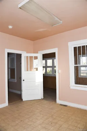 a view of an empty room with window and wooden floor