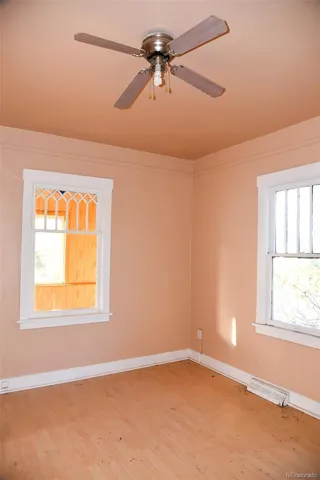 an empty room with windows and fan