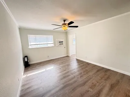 an empty room with wooden floor chandelier fan and windows