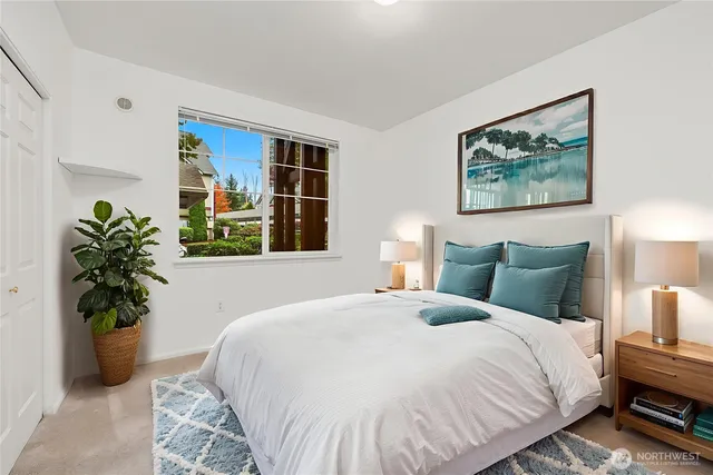 a large bed sitting in a bedroom next to a window with a potted plant