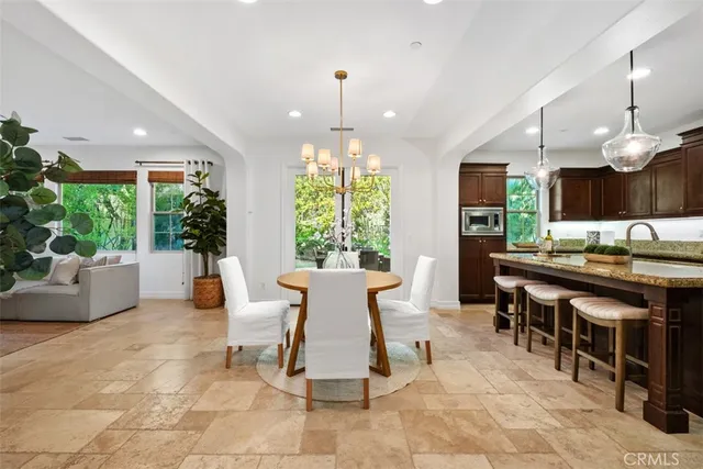 a dining room with wooden floor a chandelier a glass table and chairs