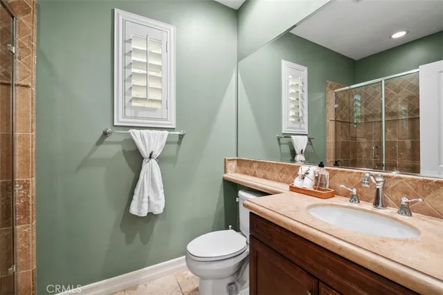 a bathroom with a granite countertop sink toilet and mirror