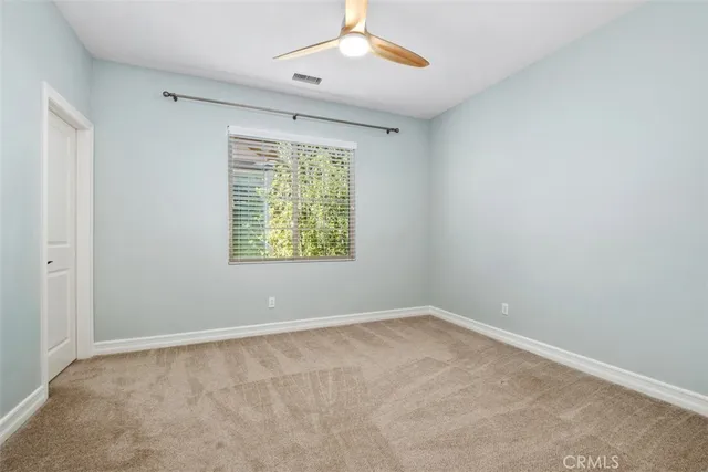 an empty room with a window and ceiling fan