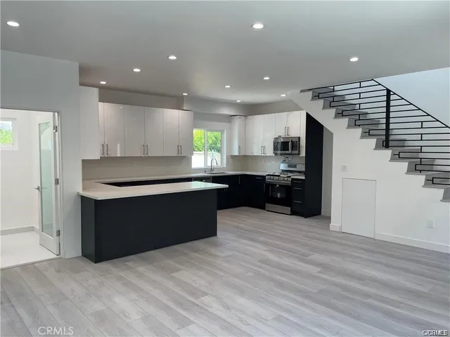 a large kitchen with stainless steel appliances granite countertop a large counter top and a wooden floors